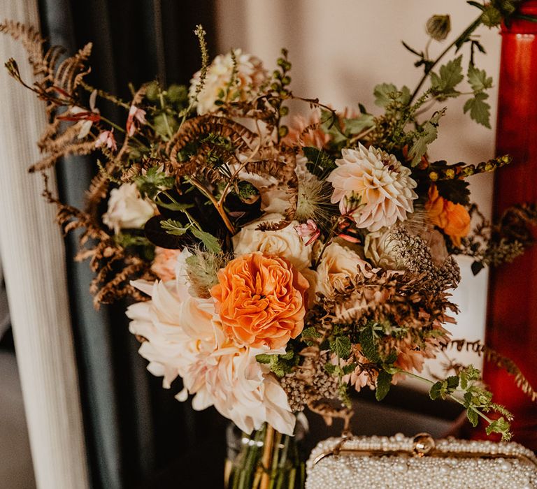 Orange and white bouquet for the bride with her pearl bridal clutch bag 