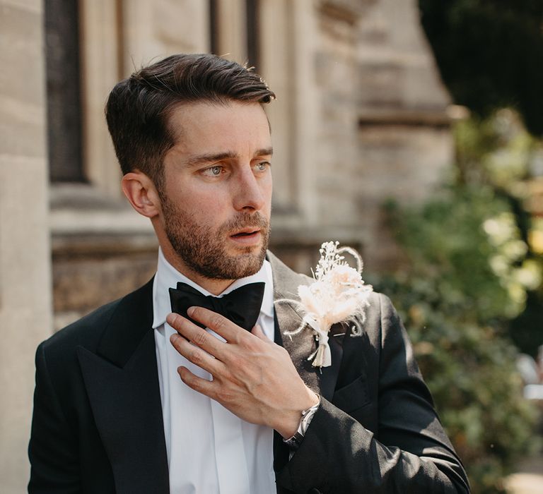 Groom in black tuxedo with boho dried flower buttonhole accessory 