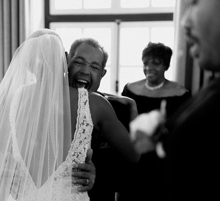 Father of the bride hugs the bride as he sees her in her wedding dress for the first time 