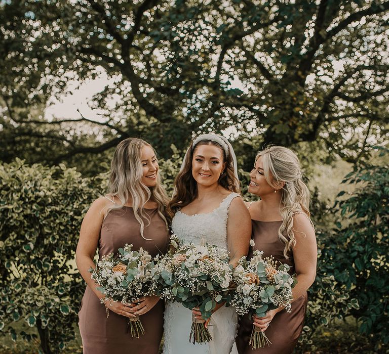 Bridal party wearing satin brown bridesmaid dresses with white wedding bouquet 