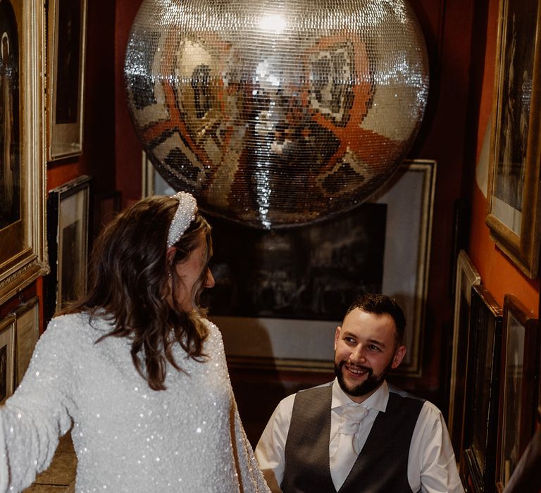 Bride in white short sequin wedding reception dress with statement pearl headband with groom 