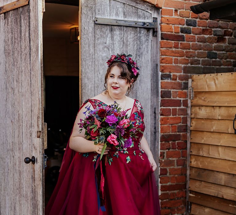 Bride in deep berry red coloured wedding dress with boho flower crown for autumnal barn wedding 