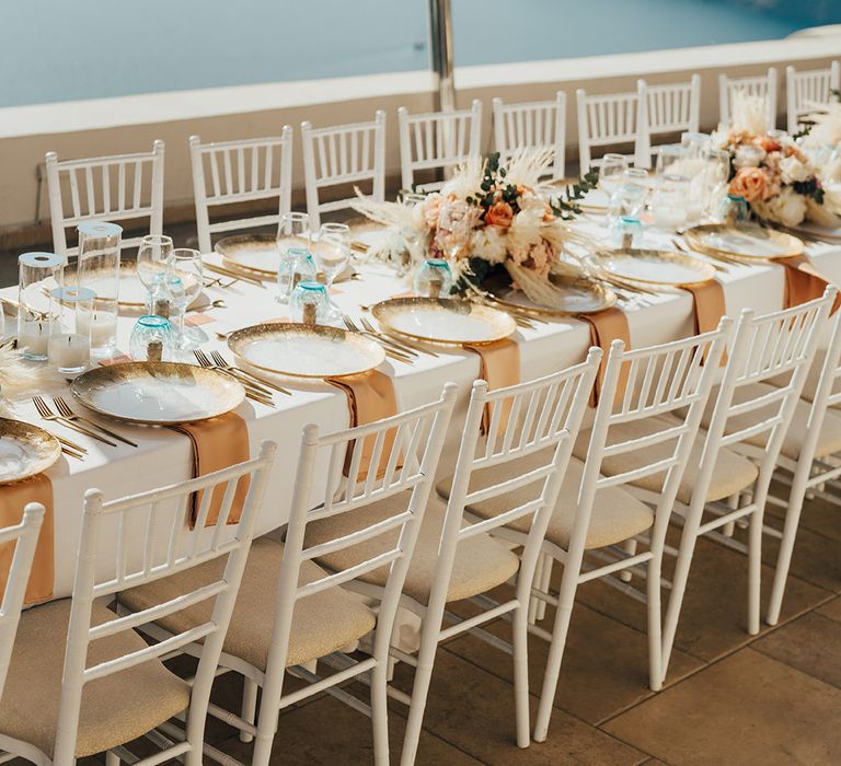 Outdoor Santorini wedding in Greece with neutral tablescape decorated with touches of gold and peach 