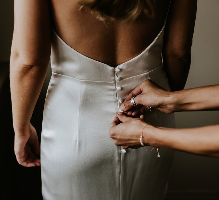 Bride wearing white satin slip wedding dress with button back detailing 