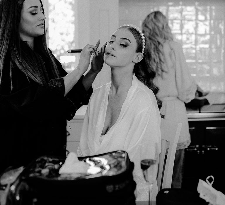 Bride in pearl headband having her makeup done 