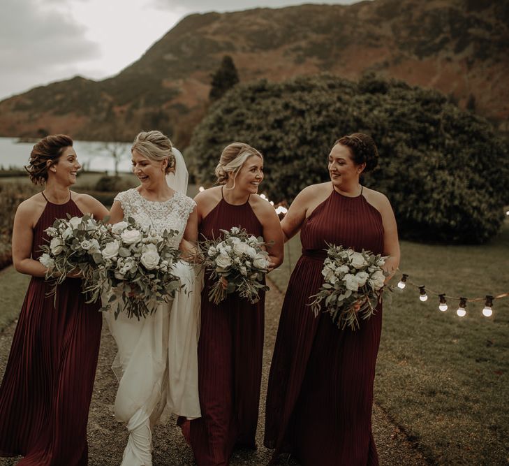 Bride and bridesmaids winter wedding shot in the Lake District with festoon lights and burgundy bridesmaid dresses