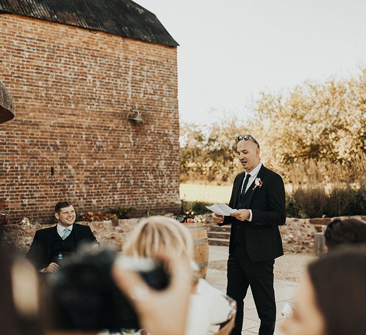 Man gives speech outdoors at a wedding