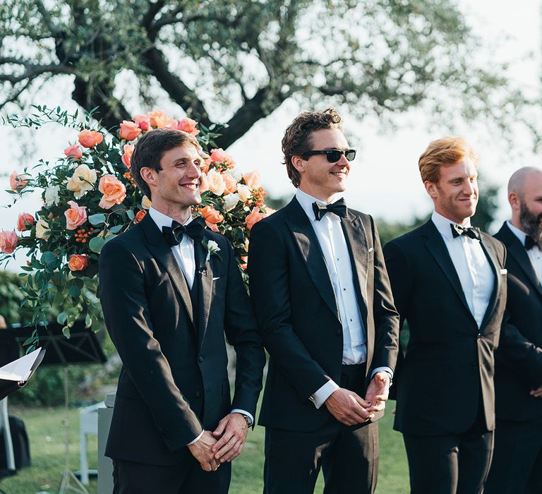 Groomsmen in tuxedos standing at the altar 