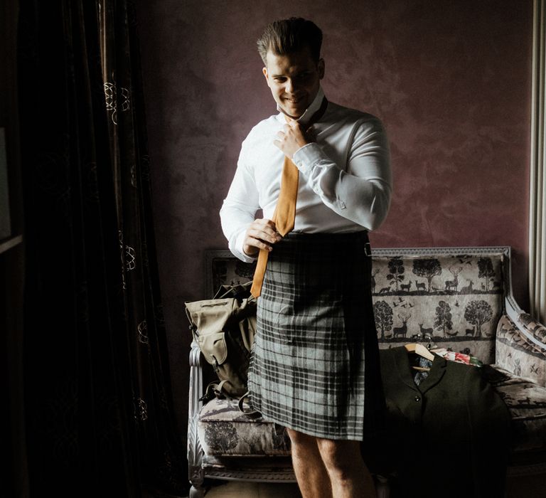 Groom gets ready on the morning of wedding wearing kilt