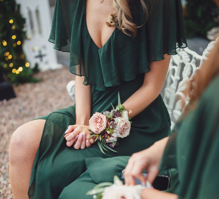 Groomsmaids in dark green dresses with pink flower corsages 