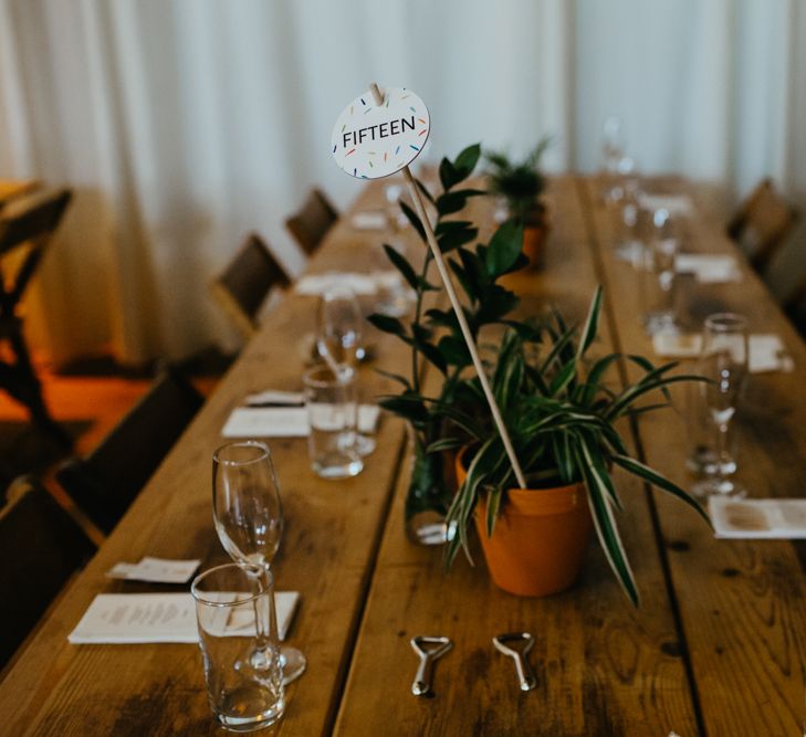 Potted plant table centrepieces with colourful table number sign 