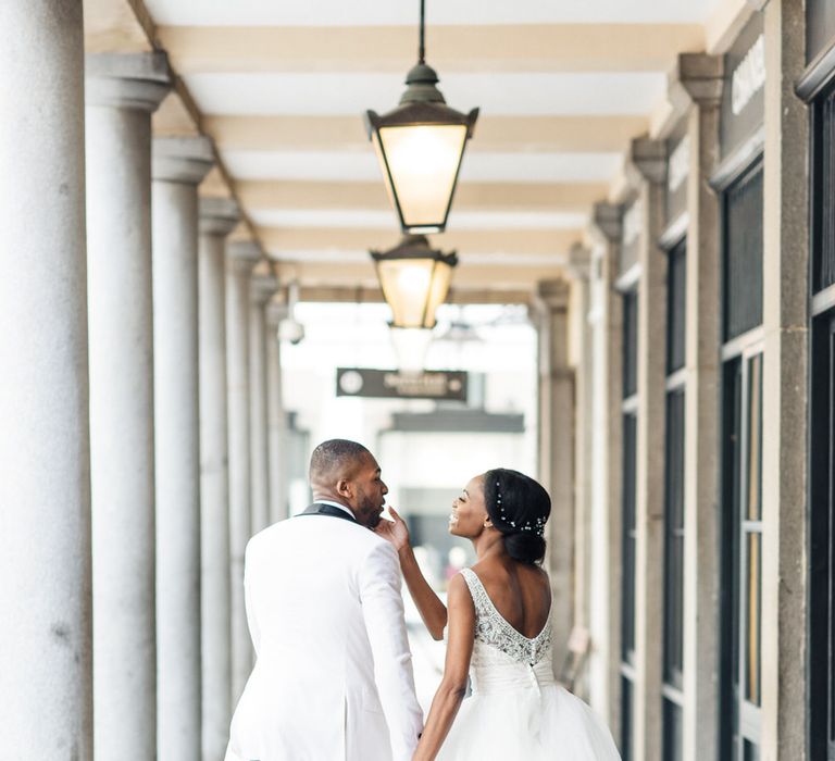 Bride & groom hold hands beneath white pillars in Covent Garden