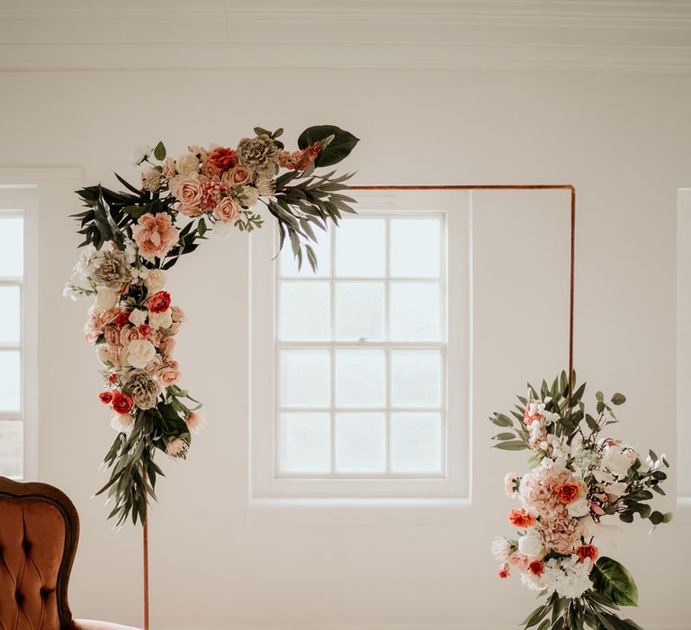 Copper frame altar with peach and white wedding flowers and foliage 