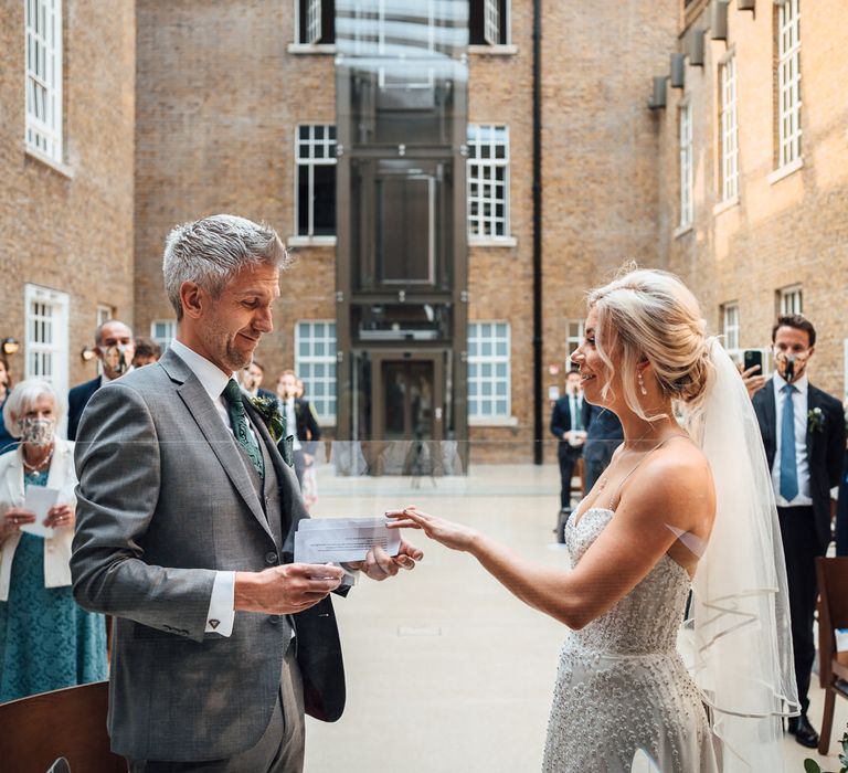 Groom places ring on wedding finger of bride during wedding ceremony