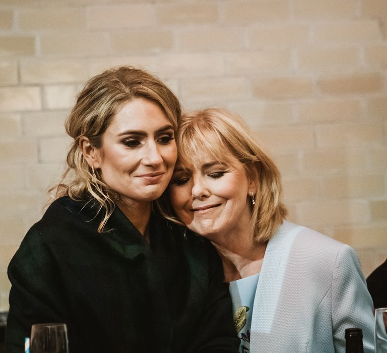 Bride sits with mother at reception party