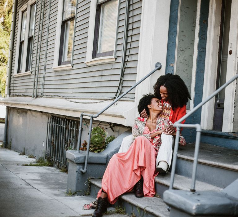 Two brides sitting on some steps during intimate engagement engagement session at Haight-Ashbury in San Francisco 