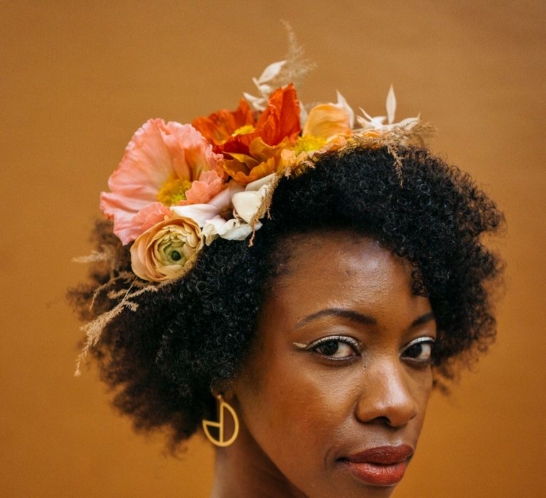 Bride with afro hair wearing a floral headpiece made of fresh flowers including orange poppies