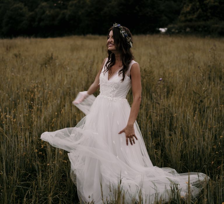 Bride stands within green fields for boho chic style image