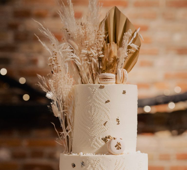 Rustic wedding cake in a wooden tree slice cake stand with dried flower and macaroon decor. 