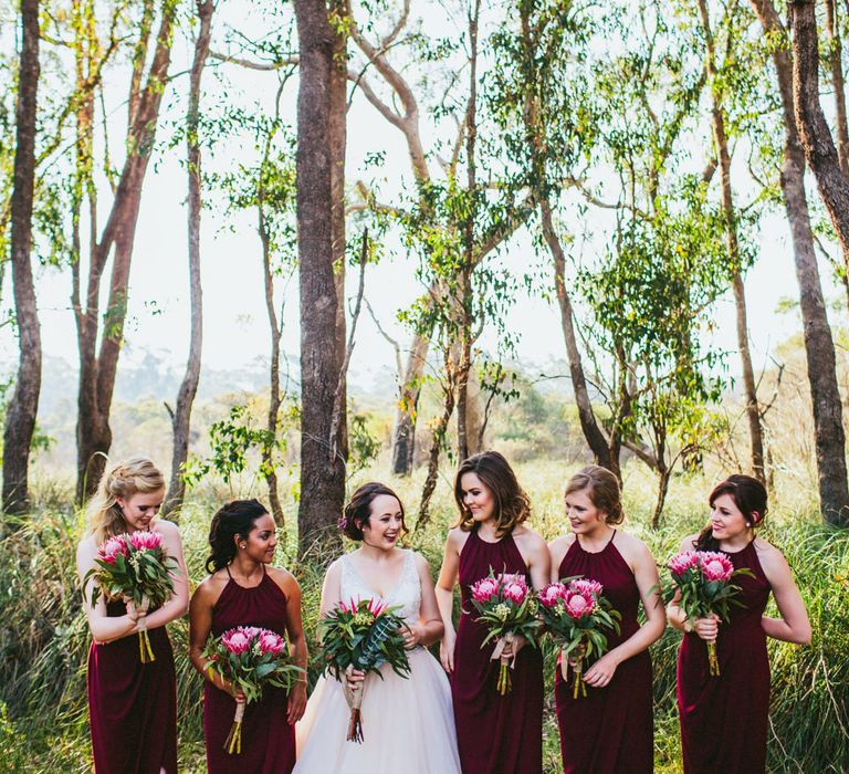 Bridesmaids in halterneck burgundy dresses with front wrap detail at woodland wedding 