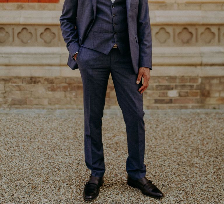 Indian groom in a three-piece blue suit with burgundy bow tie and pocket square 