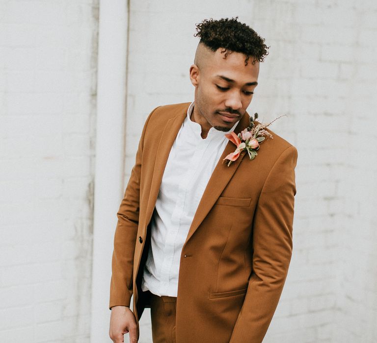 Groom in a white grandad shirt and dark orange suit wearing a peach buttonhole flower 