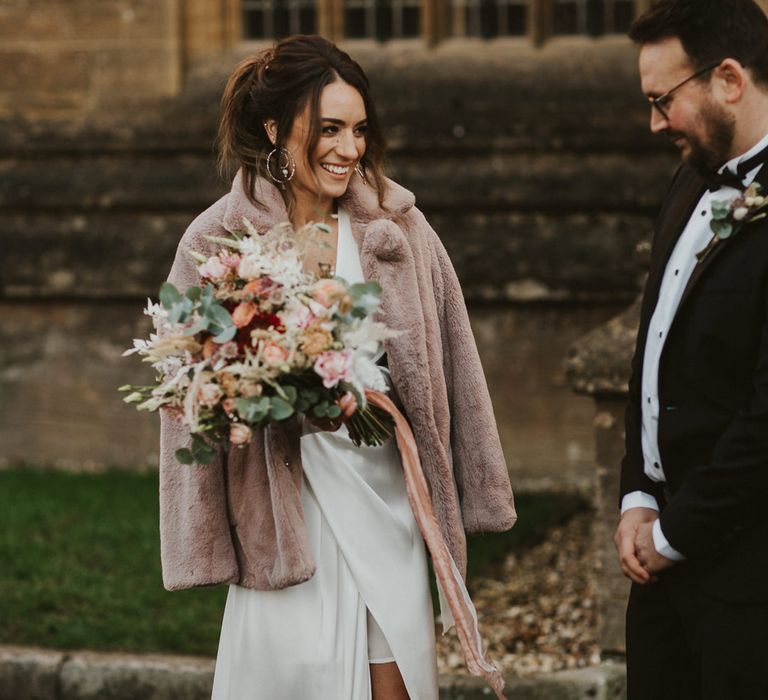 New Years Eve intimate wedding with stylish bride in a wrap wedding dress and beige faux fur coat