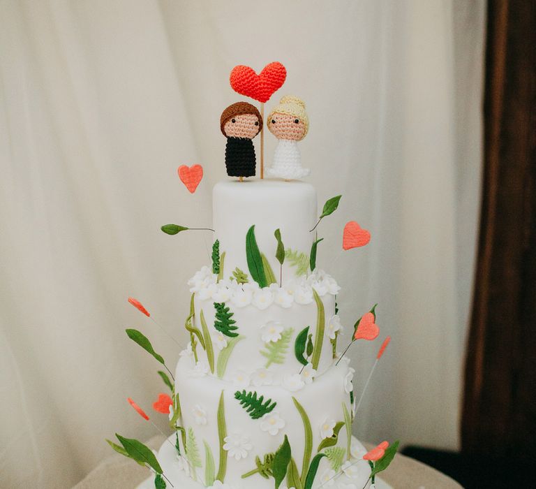 Iced wedding cake with foliage wedding decor and crochet people wedding cake toppers 