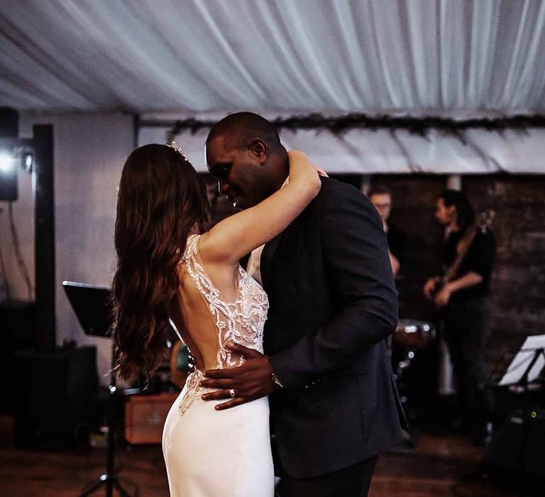 Bride wears silk fitted to her body low detailed back wedding dress as dances with her new husband