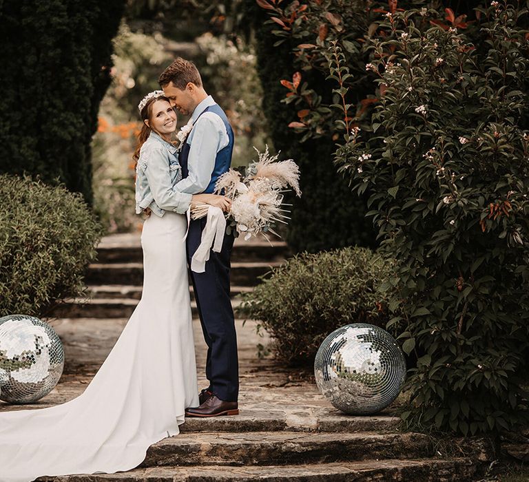 Bride & groom stand on staircase outdoors and kiss on their wedding day