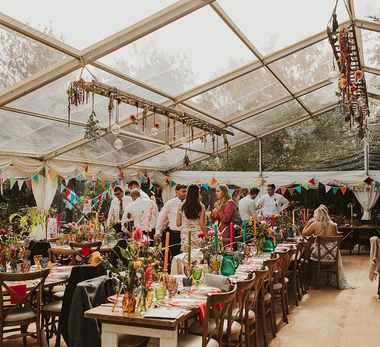 colourful back garden clear marquee wedding reception with vibrant decor 