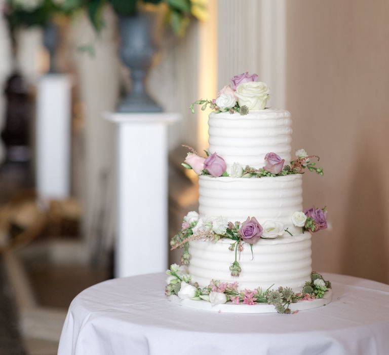 Three tier wedding cake complete with white frosting and floral decor