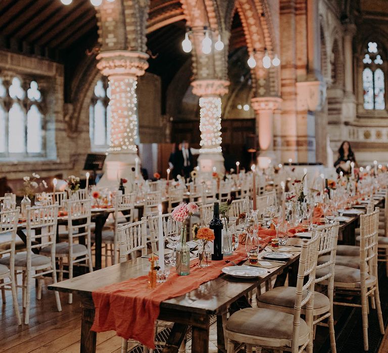 Brightly coloured orange table runner lines wooden rustic tables complete with brightly coloured floral flowers 