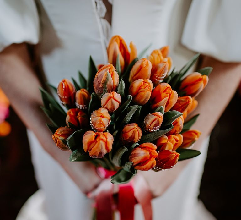 bride holding a orange and red tulip bouquet 