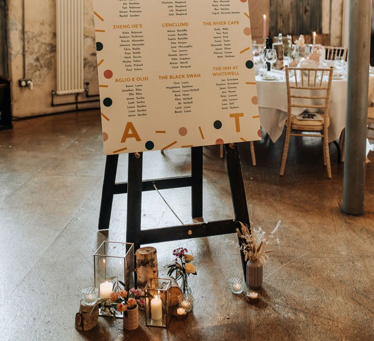 Modern wedding table plan with bold confetti pattern on black easel fo industrial style wedding reception at Holmes Mill wedding venue