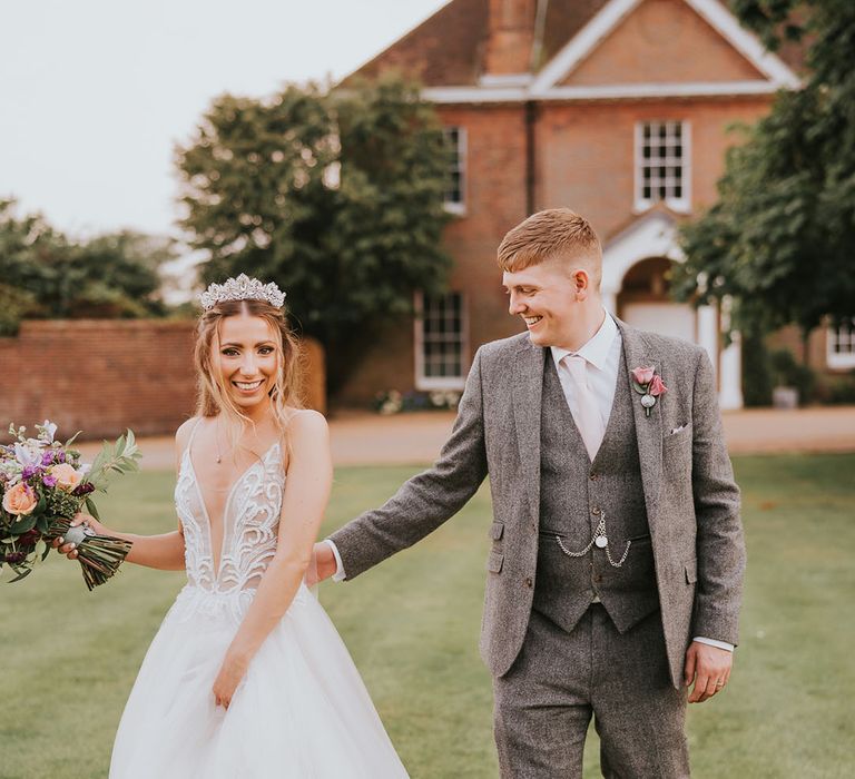 Bride in sparkly plunging deep v-neck tulle wedding dress and groom in grey tweed suit with pink tie