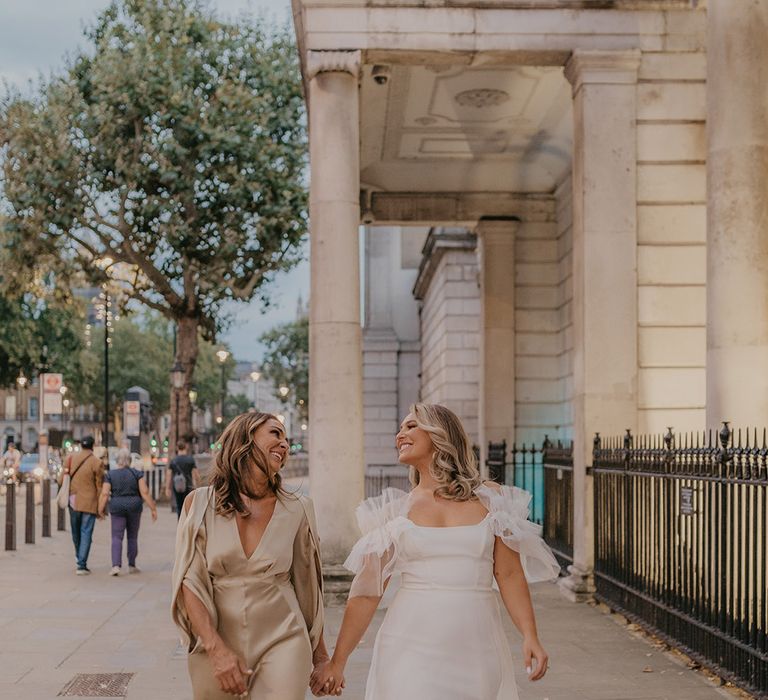 Bride in Halfpenny London wedding dress walks with her mother in gold jumpsuit around London