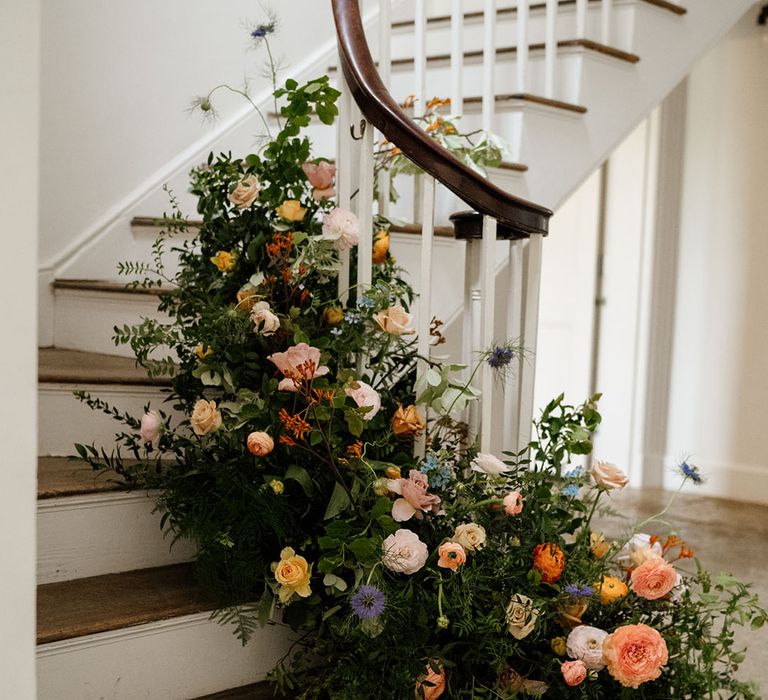 Colourful and bright flowers and greenery on the stairs of Aswarby Rectory wedding venue 