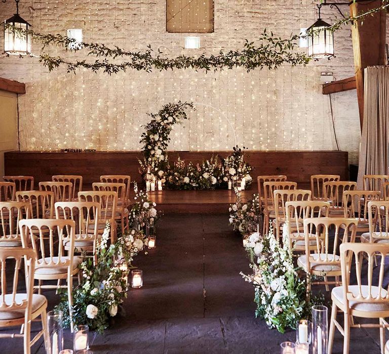 East Riddlesden Hall barn wedding ceremony with fairy light back drop, hoop floral arch, candles and greenery 