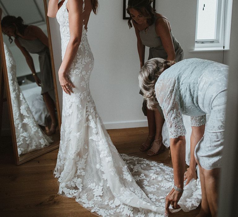 Bride wears her red hair tied back with fishtail braids to either side and embellished hair accessories are pinned to the back 