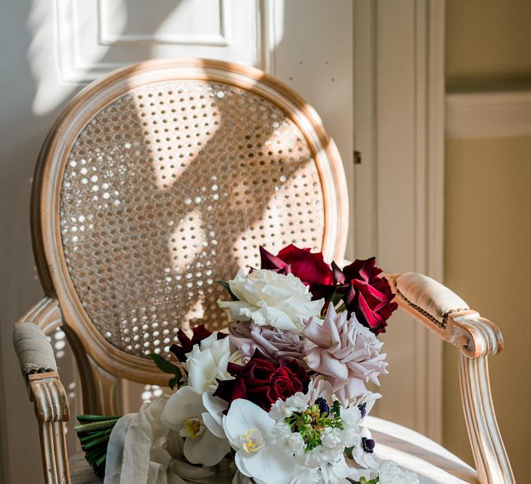 White, red and pastel pink bouquet filled with roses and orchids tied with white ribbon  