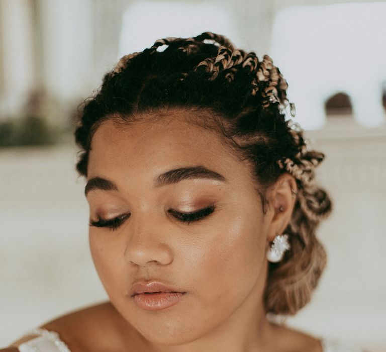 Bride with soft and glowy wedding makeup with pearl earrings and her braids in an updo 