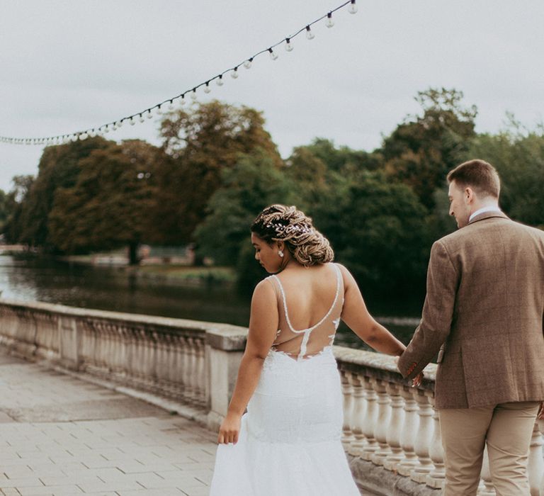 Bride in an illusion back sparkly wedding dress walking with the groom in a brown checkered suit 