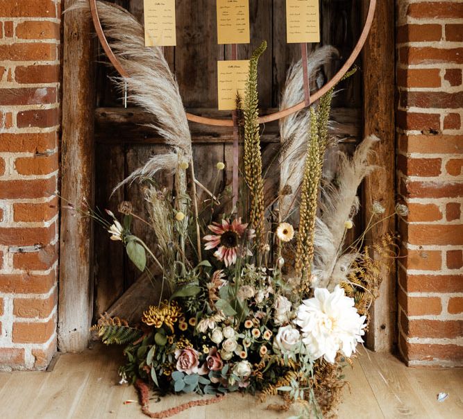 Wooden circular hanging wedding table plan with neutral floral decorative bouquet