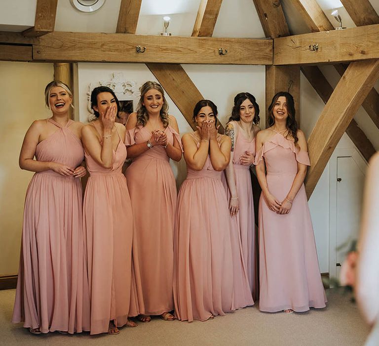 Bridesmaids in pink dresses get their first look at the bride 