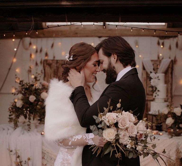 A rustic winter wedding with the bride wearing a white fur shawl and the groom in black tie for the evening 