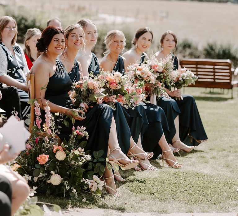 Bridesmaids wear cold shoulder dresses as they hold brightly coloured floral bouquets 