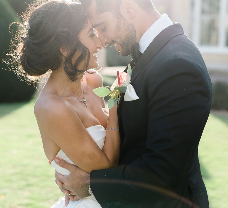 Bride & groom embrace outdoors as the sun shines around them at Syon Park