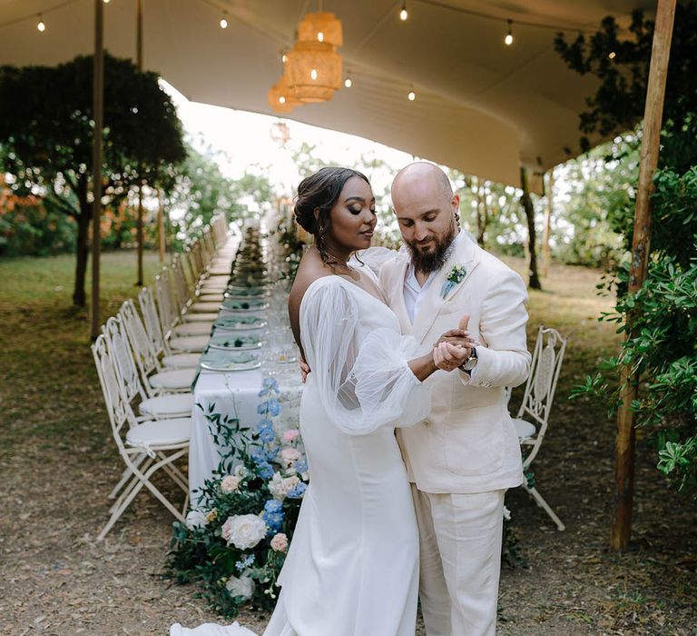 The happy couple dance in front of dinner setting at outdoor reception in Italy