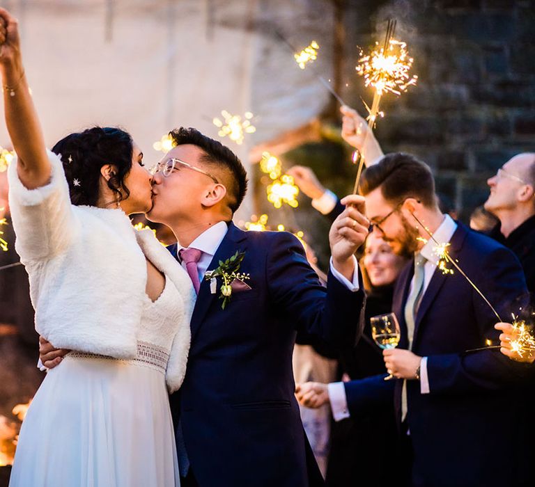 Bride wears faux fur stole and kisses her groom during sparkler exit 